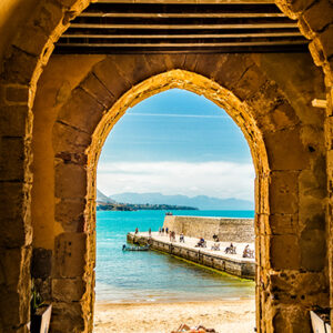 Archway,Through,An,Ancient,Stone,Building,Leading,To,A,Beach